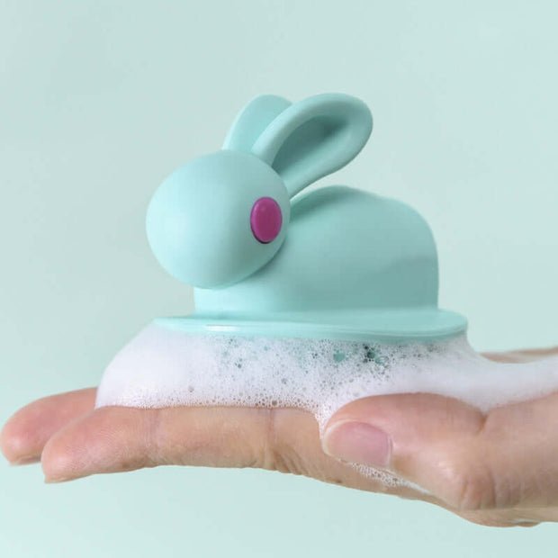 Soft Rubber Shampoo Brush for Kids' Scalp Massage with a cute bunny design in a hand with bubbles.